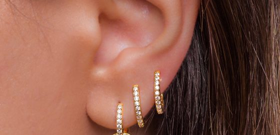 Woman ear with mulriple piercings wearing beautiful earrings with zirconia- details capture